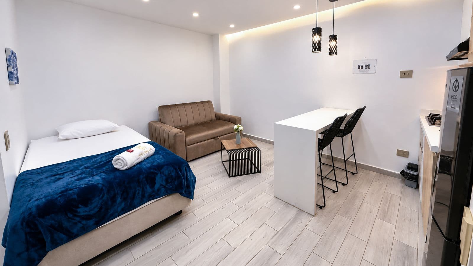 Cama, sofá café y barra de cocina