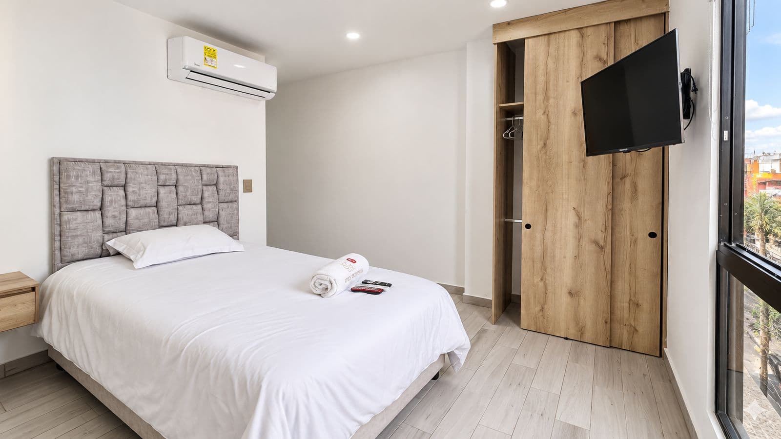 Cama con cabecero gris, clóset y aire